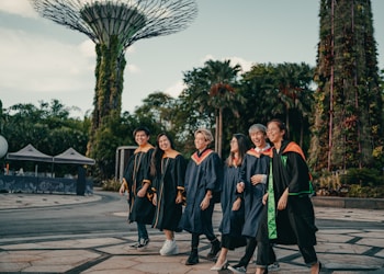 group of people in black academic dress standing on gray concrete pavement during daytime