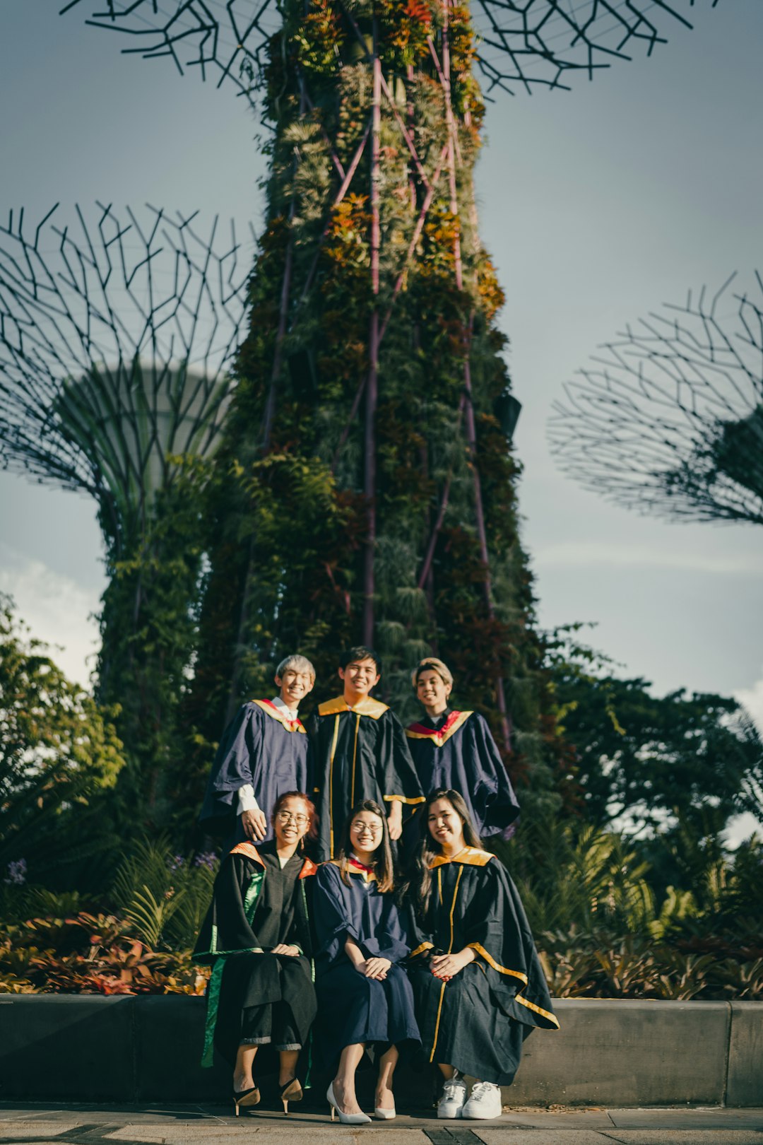 3 women in black and brown dress standing near green trees during daytime