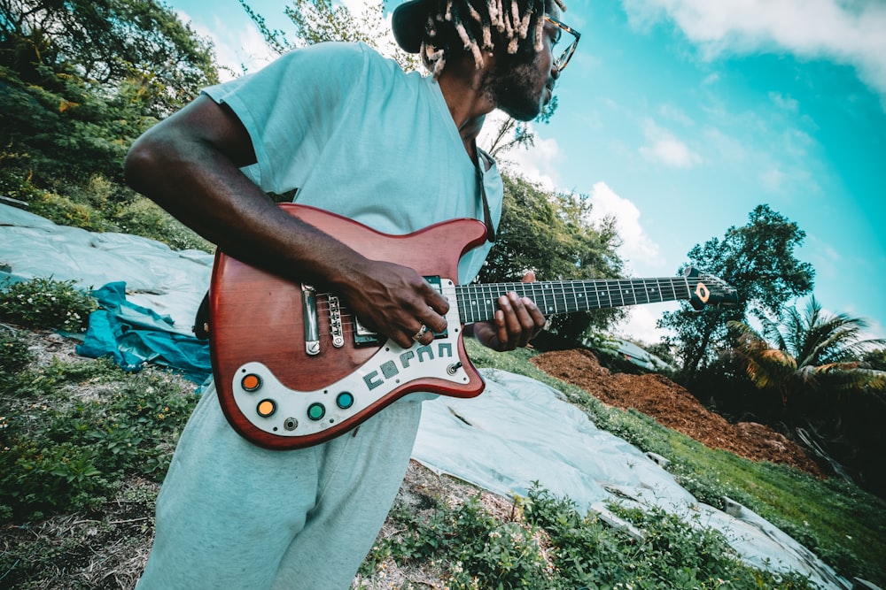 man in white t-shirt playing red and white stratocaster electric guitar