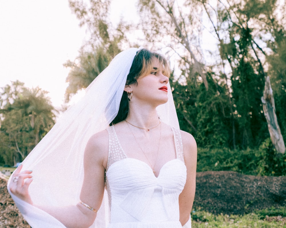 woman in white spaghetti strap dress standing on green grass field during daytime