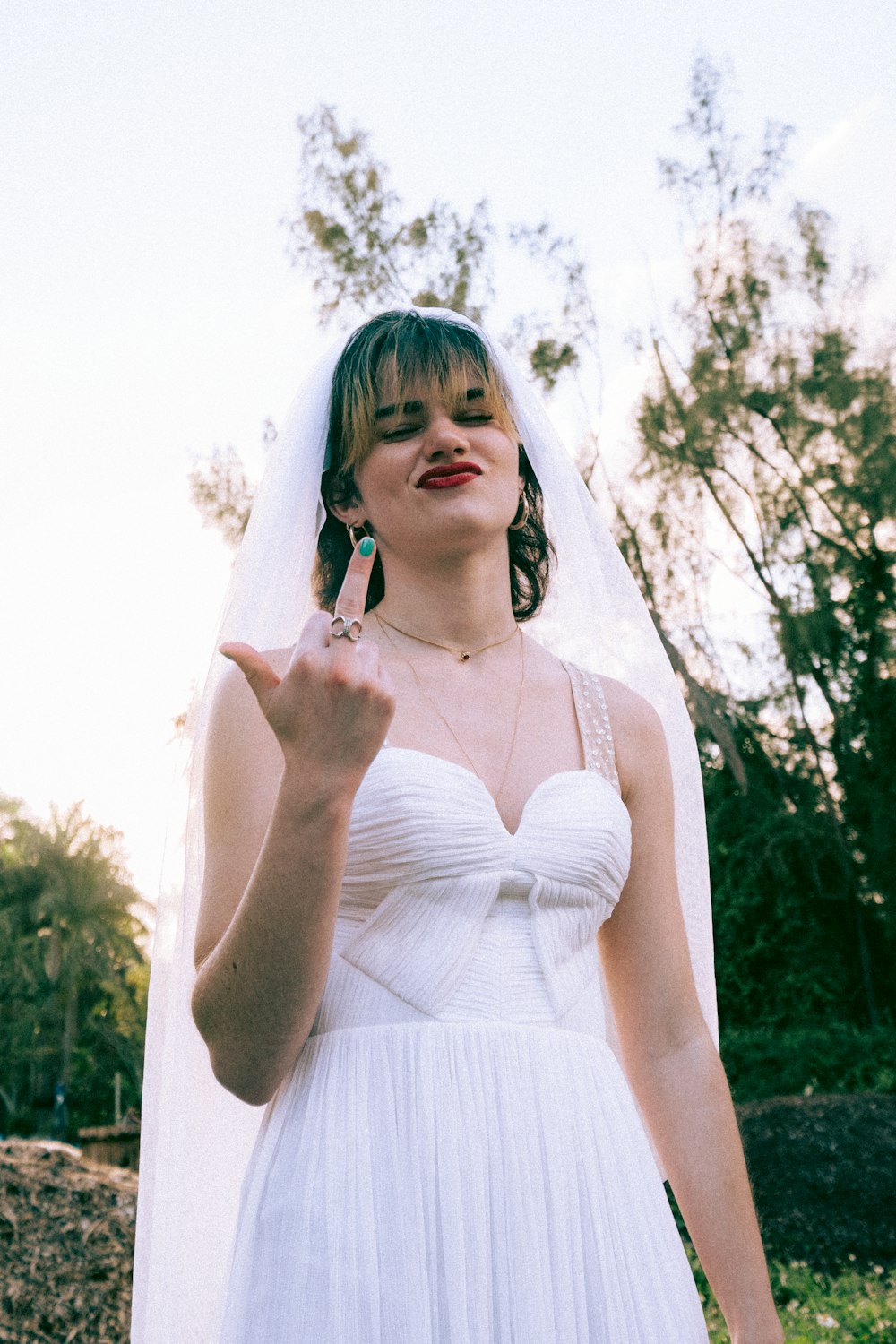 woman in white spaghetti strap dress standing near trees during daytime