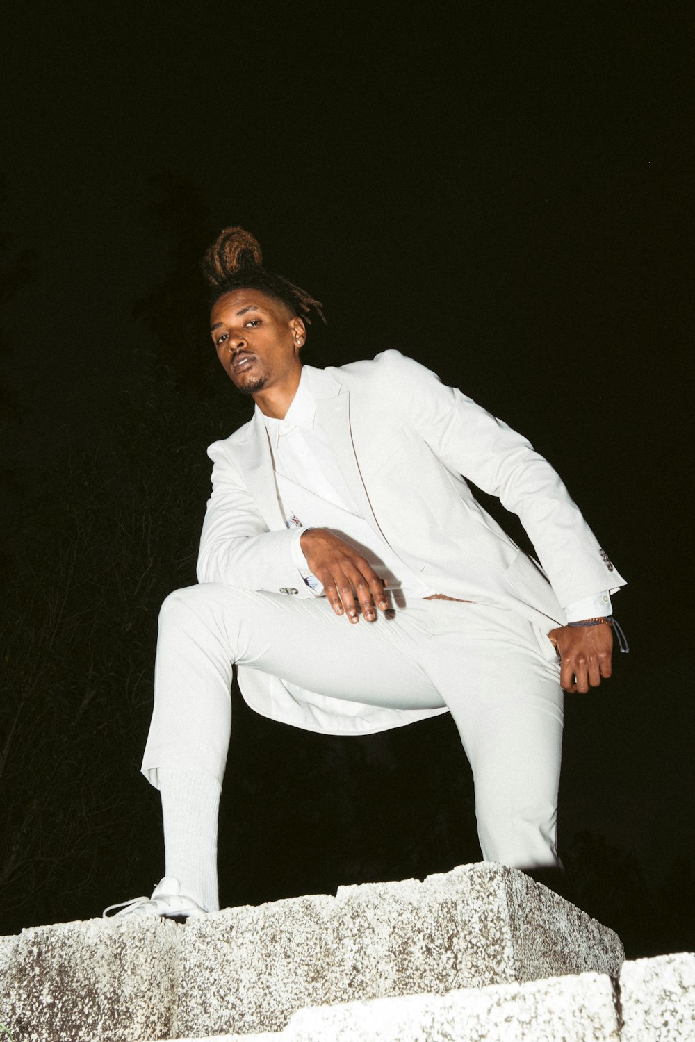 man in white suit sitting on black surface