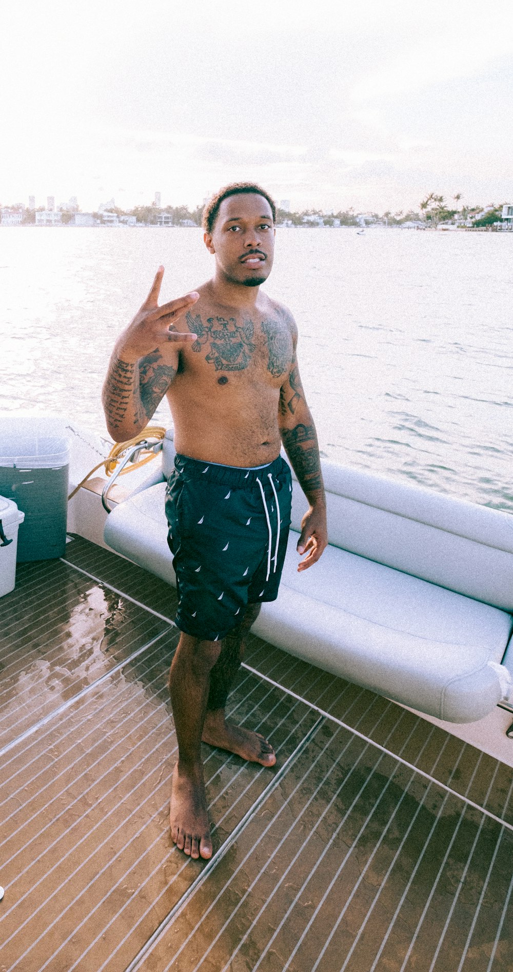 man in blue shorts standing on brown wooden dock during daytime