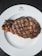 A close-up of a perfectly grilled steak on a wooden plate.
