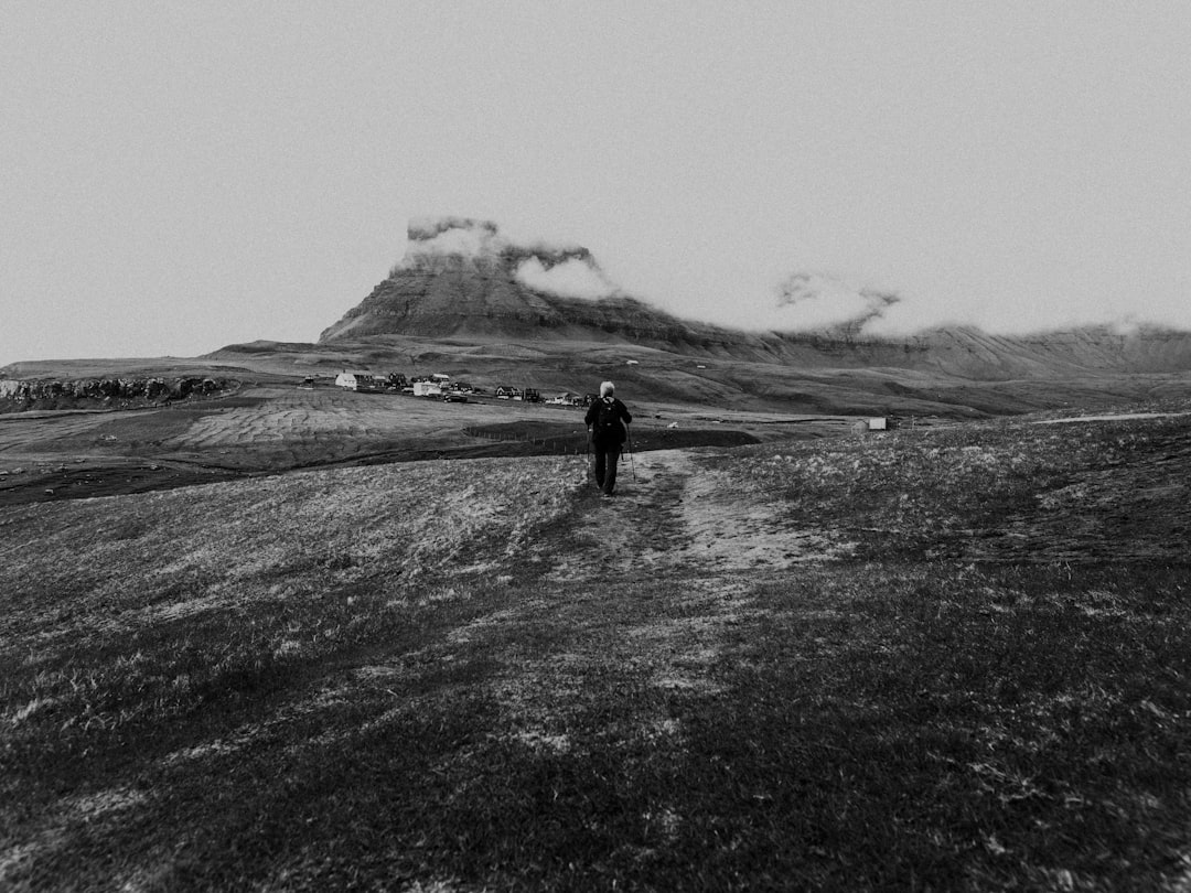 grayscale photo of person walking on grass field