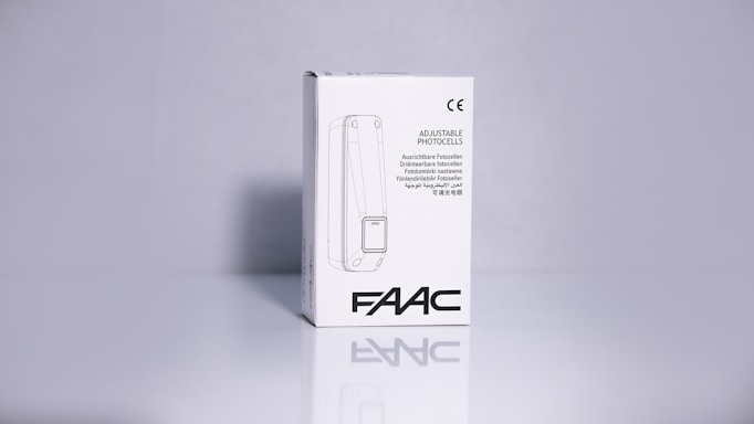 A product packaging box with a white background displaying the brand name 'FAAC' and the text 'Adjustable Photocells' along with translations in multiple languages. The image features clean lines and a minimalistic design with the CE certification mark visible.