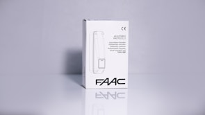 A product packaging box with a white background displaying the brand name 'FAAC' and the text 'Adjustable Photocells' along with translations in multiple languages. The image features clean lines and a minimalistic design with the CE certification mark visible.