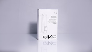 A product packaging box with a white background displaying the brand name 'FAAC' and the text 'Adjustable Photocells' along with translations in multiple languages. The image features clean lines and a minimalistic design with the CE certification mark visible.