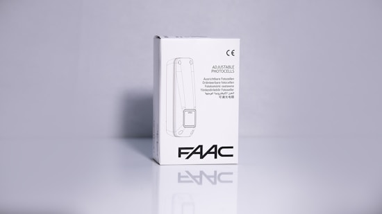 A product packaging box with a white background displaying the brand name 'FAAC' and the text 'Adjustable Photocells' along with translations in multiple languages. The image features clean lines and a minimalistic design with the CE certification mark visible.
