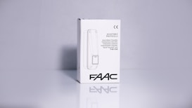 A product packaging box with a white background displaying the brand name 'FAAC' and the text 'Adjustable Photocells' along with translations in multiple languages. The image features clean lines and a minimalistic design with the CE certification mark visible.
