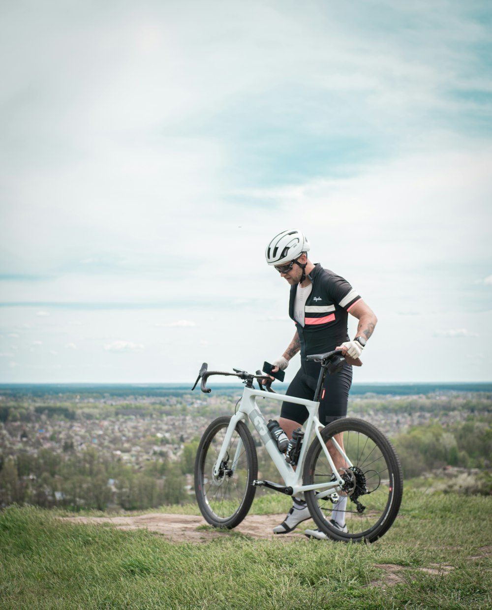 man in black shirt riding white bicycle on green grass field during daytime