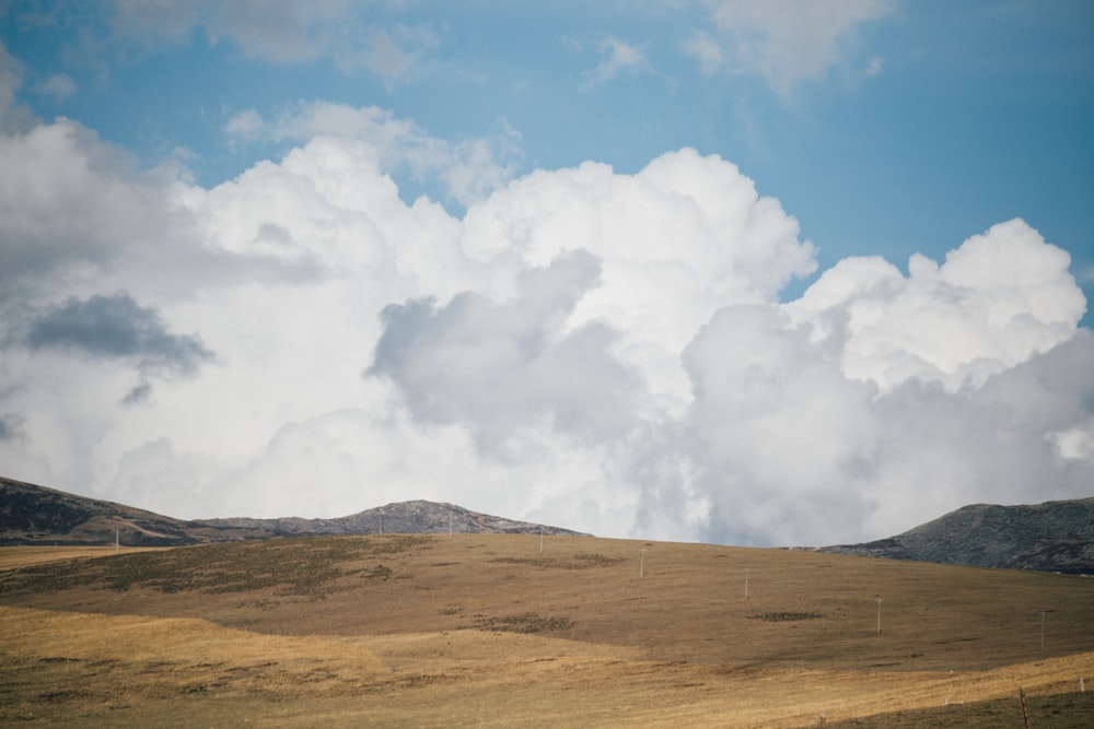 Weiße Wolken über braunem Feld