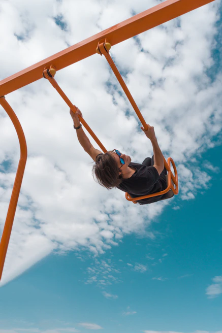 Close-up of a bright orange swing set with children playing happily