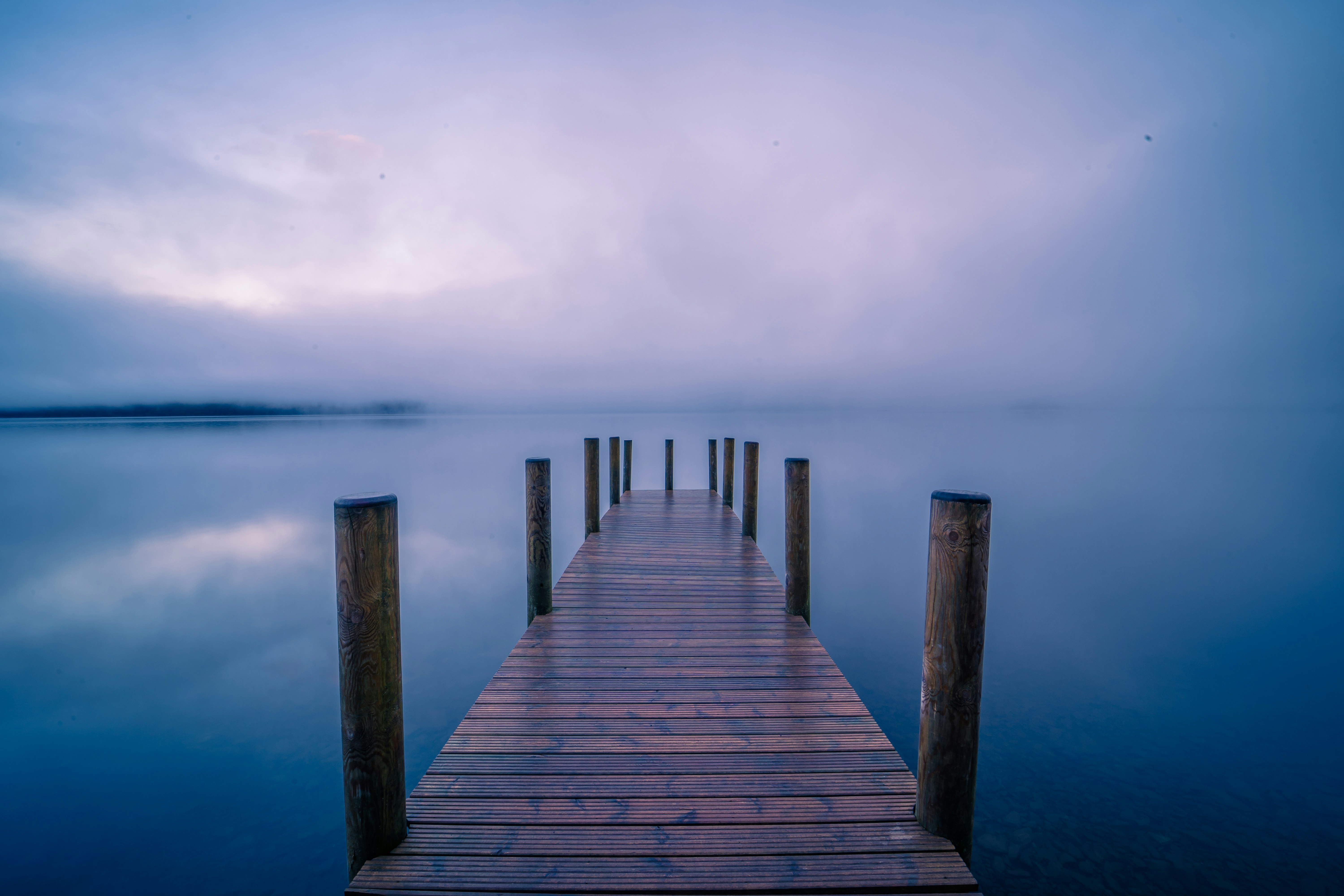 brown wooden dock on sea under white sky during daytime