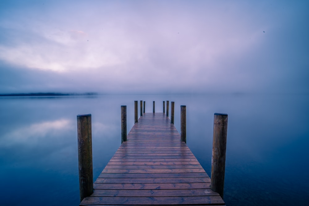 brown wooden dock on sea under white sky during daytime