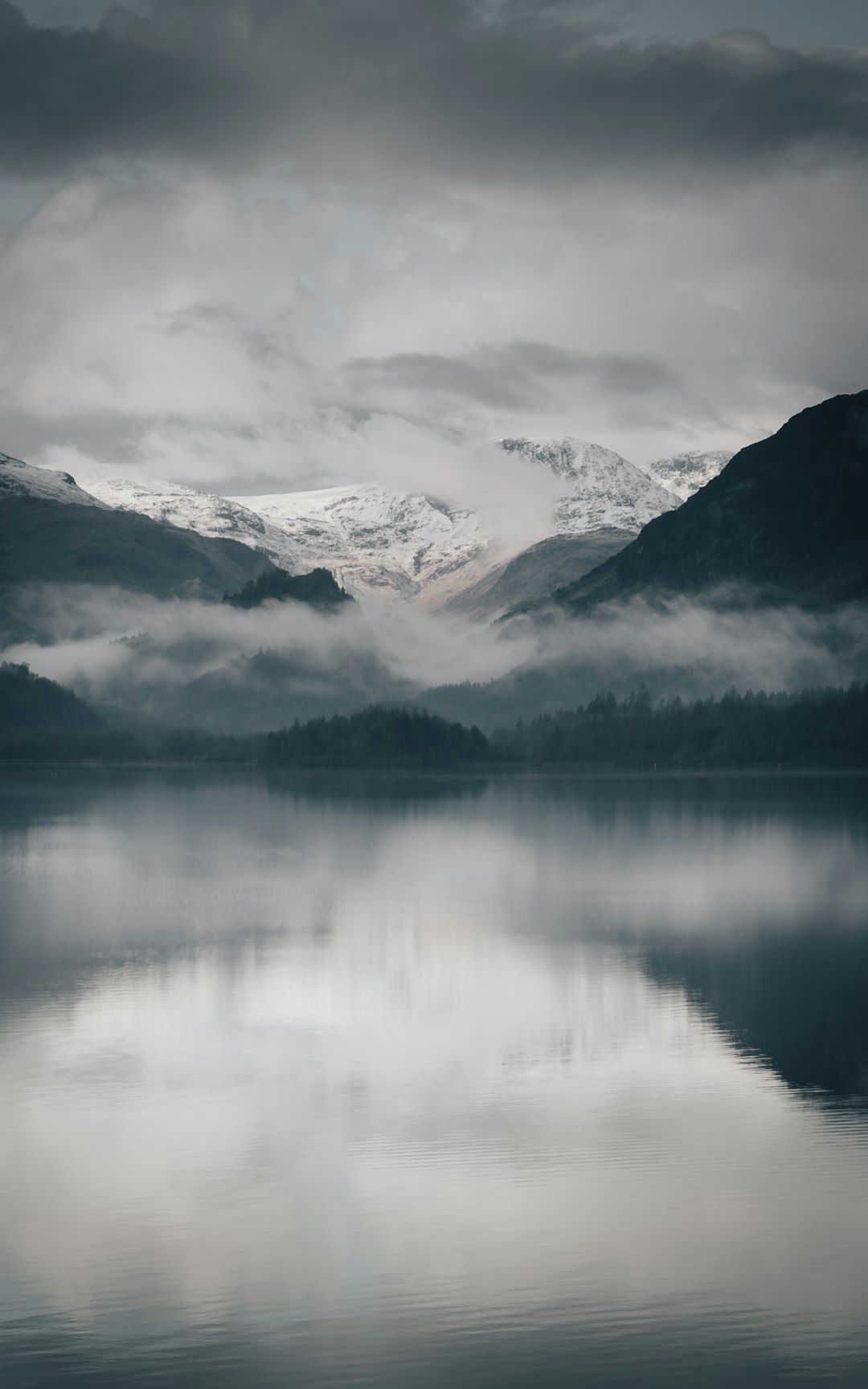 body of water near mountain range covered with snow during daytime