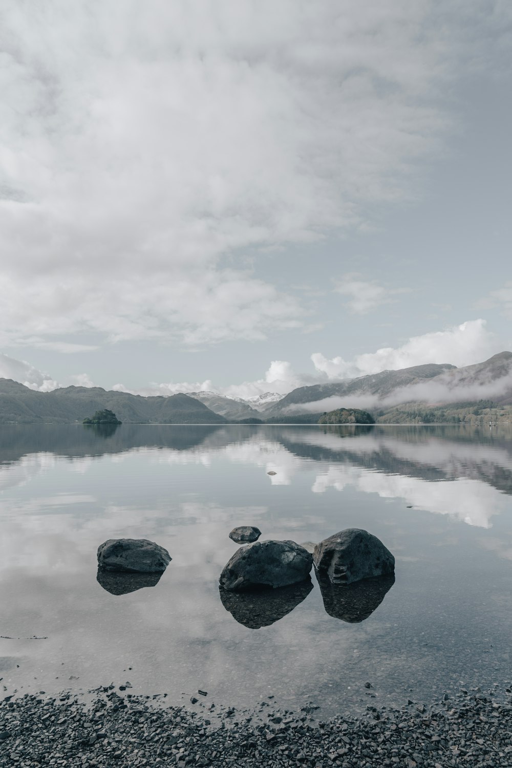 corpo d'acqua vicino alla montagna sotto il cielo bianco durante il giorno