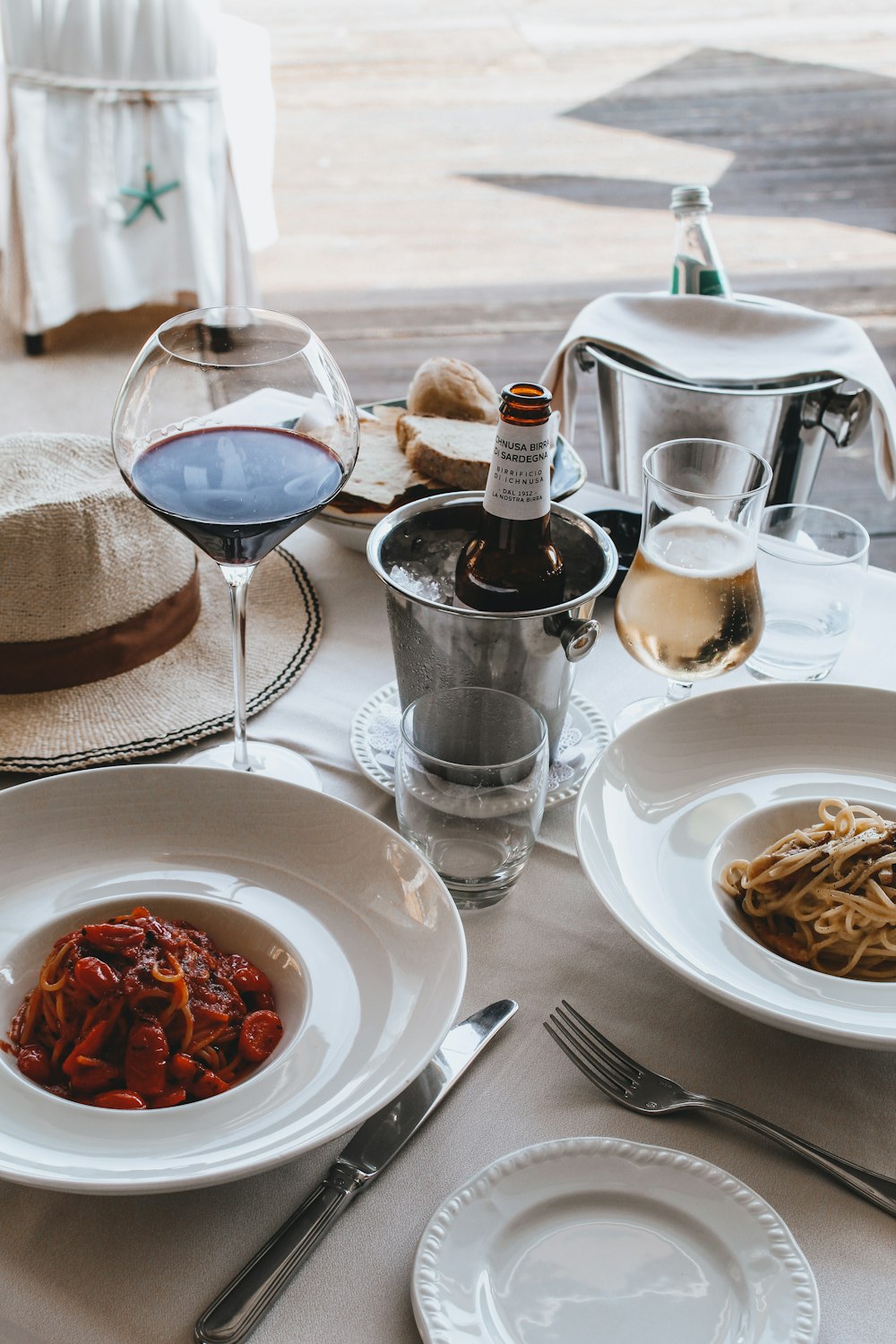 Pasta auf weißem Keramikteller neben Weinglas und Weinflasche