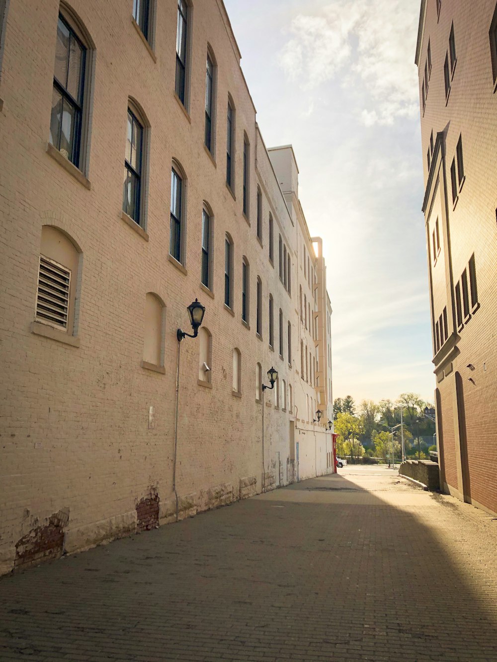 gray concrete road between white concrete buildings during daytime