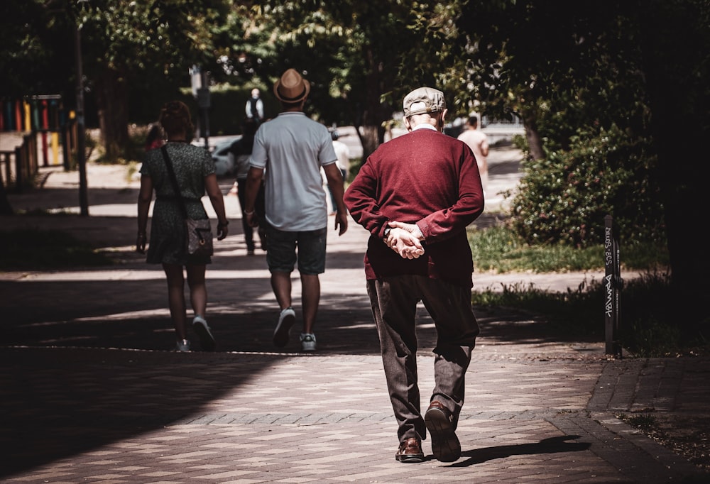 man in red hoodie walking on sidewalk during daytime