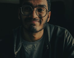 man in black zip up jacket wearing black framed eyeglasses