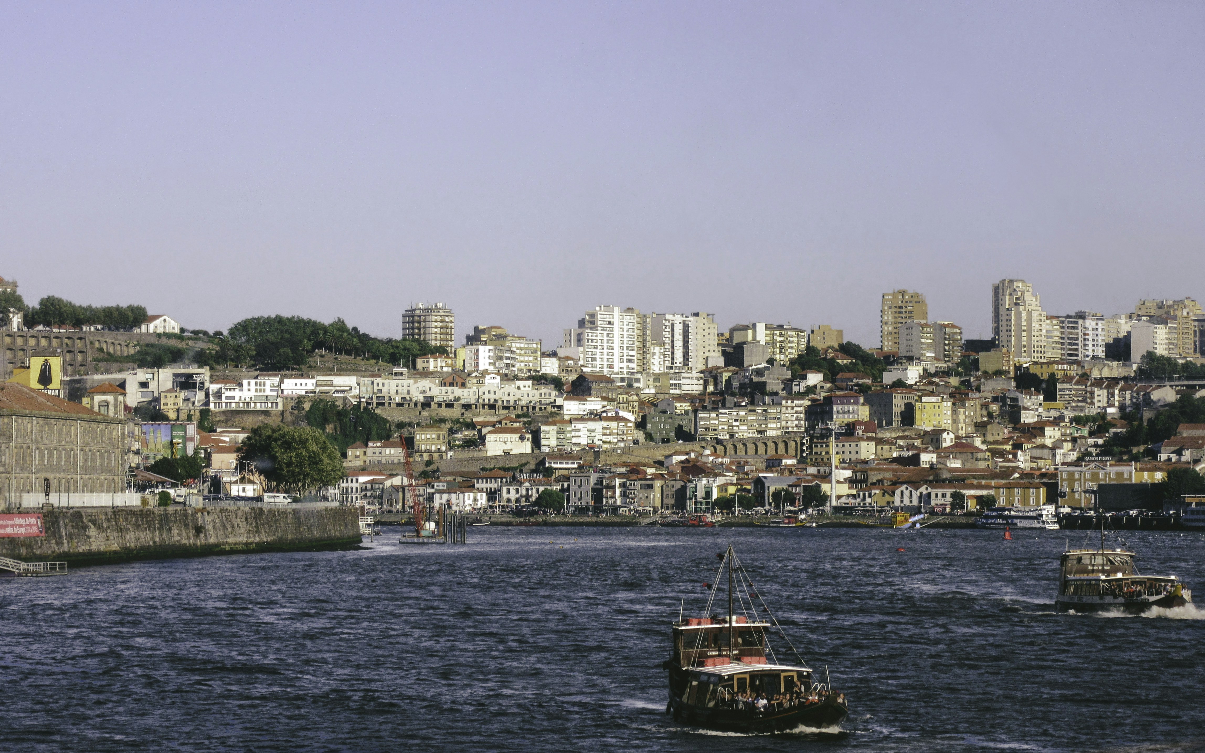 red and black boat on body of water near city buildings during daytime