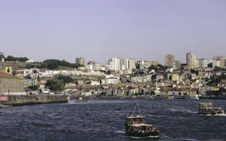red and black boat on body of water near city buildings during daytime