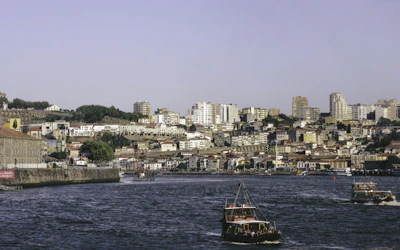 red and black boat on body of water near city buildings during daytime