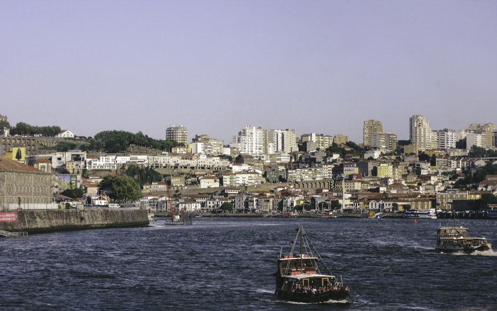 red and black boat on body of water near city buildings during daytime