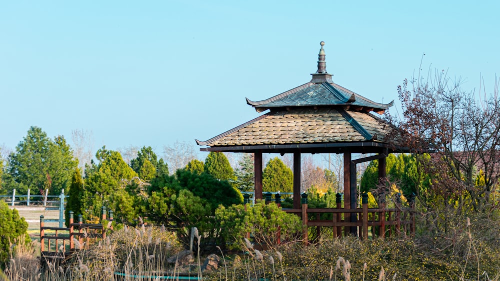 brown and black gazebo surrounded by green trees during daytime