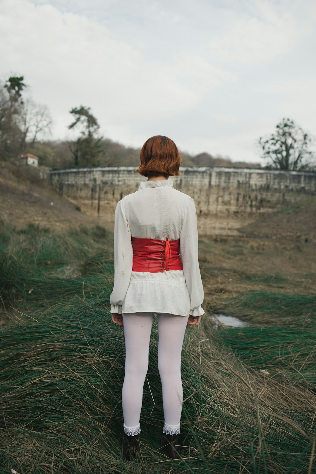 woman in white long sleeve shirt and white skirt walking on green grass field during daytime