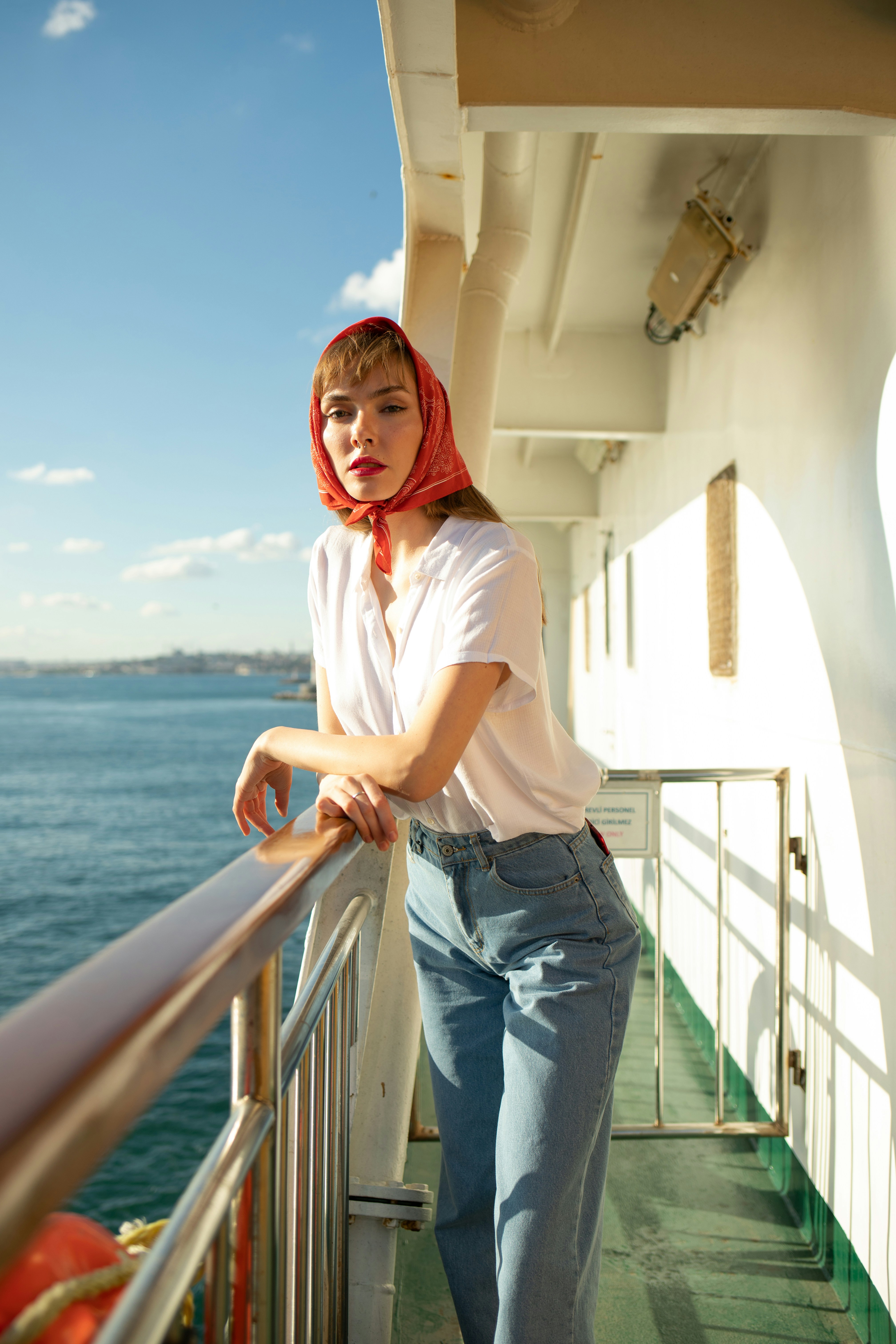 woman in white shirt and blue denim shorts standing on white wooden railings during daytime
