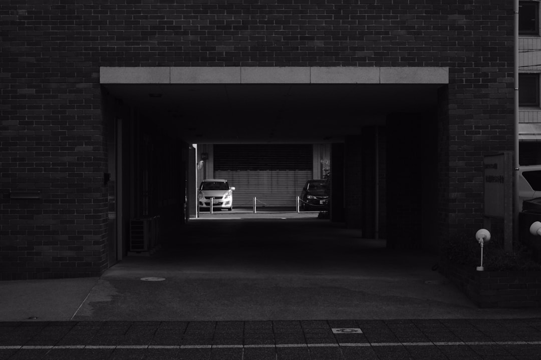 grayscale photo of man sitting on bench in front of window