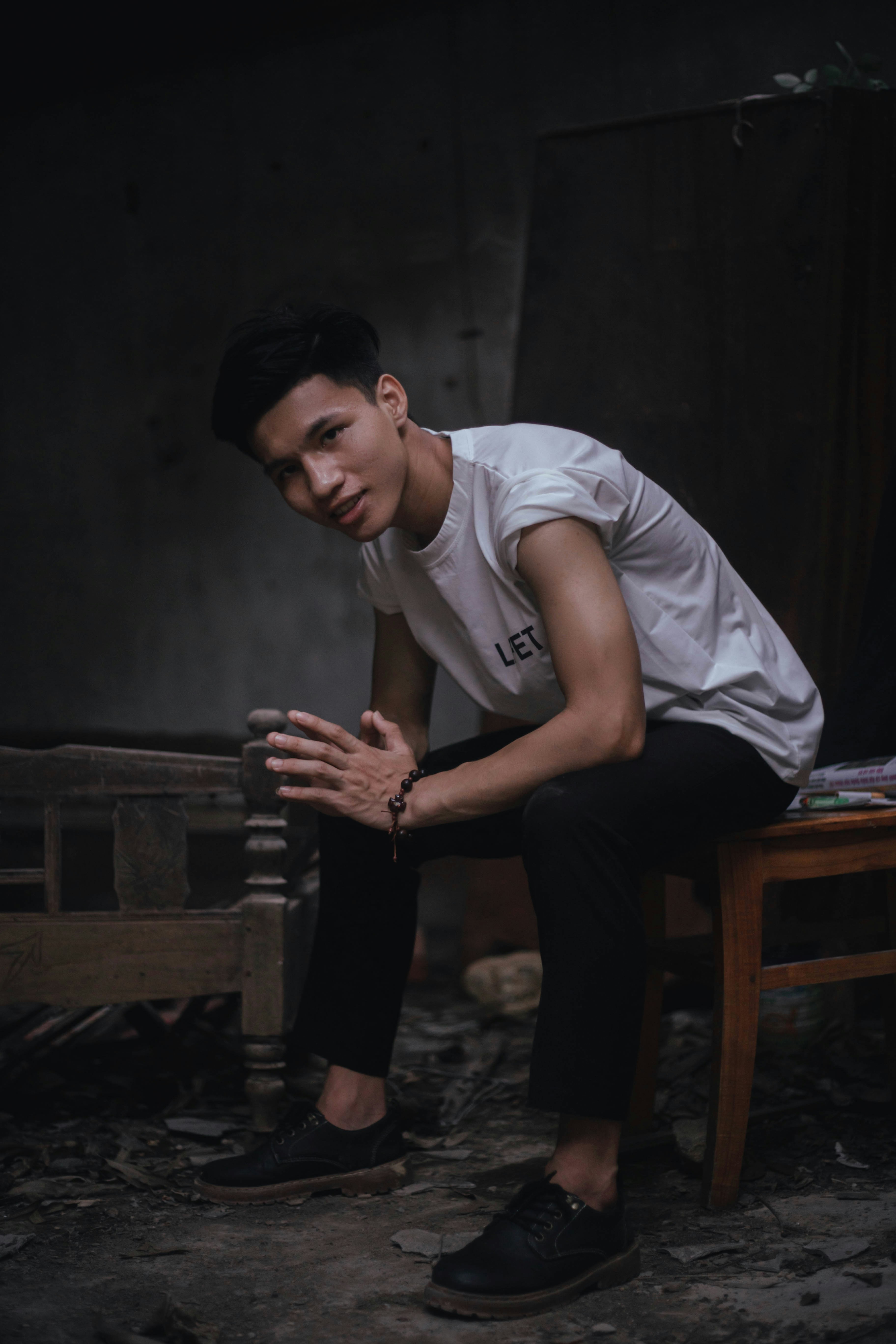 man in white crew neck t-shirt and black pants sitting on brown wooden chair