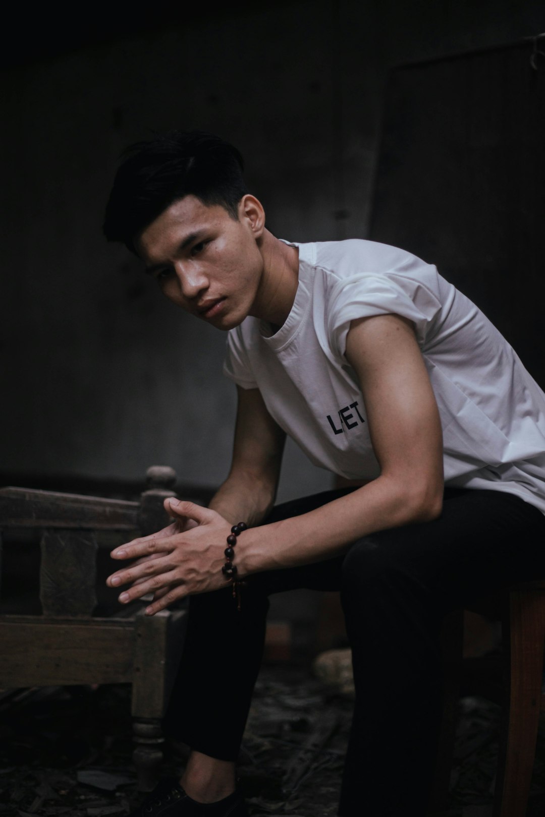 man in white crew neck t-shirt and black pants sitting on brown wooden bench