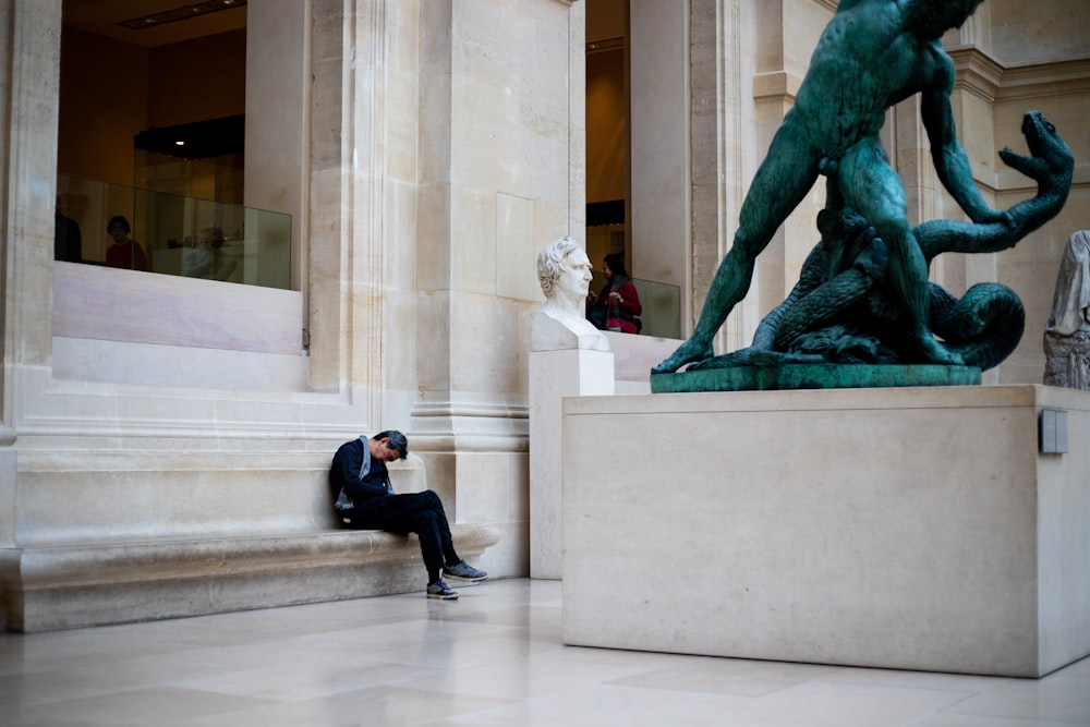 a man sitting on the ground next to a statue