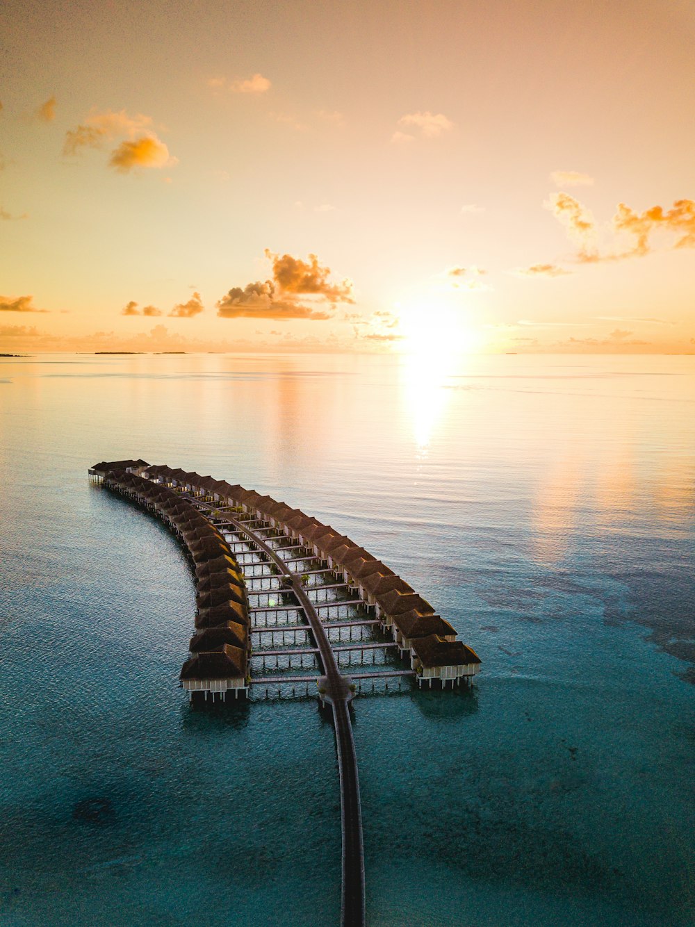 brown wooden dock on body of water during sunset