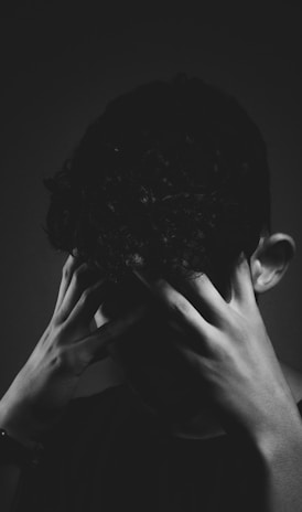 grayscale photo of man covering his face with his hand