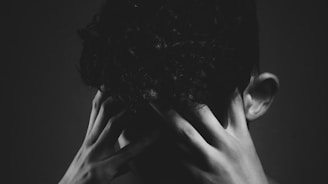 grayscale photo of man covering his face with his hand