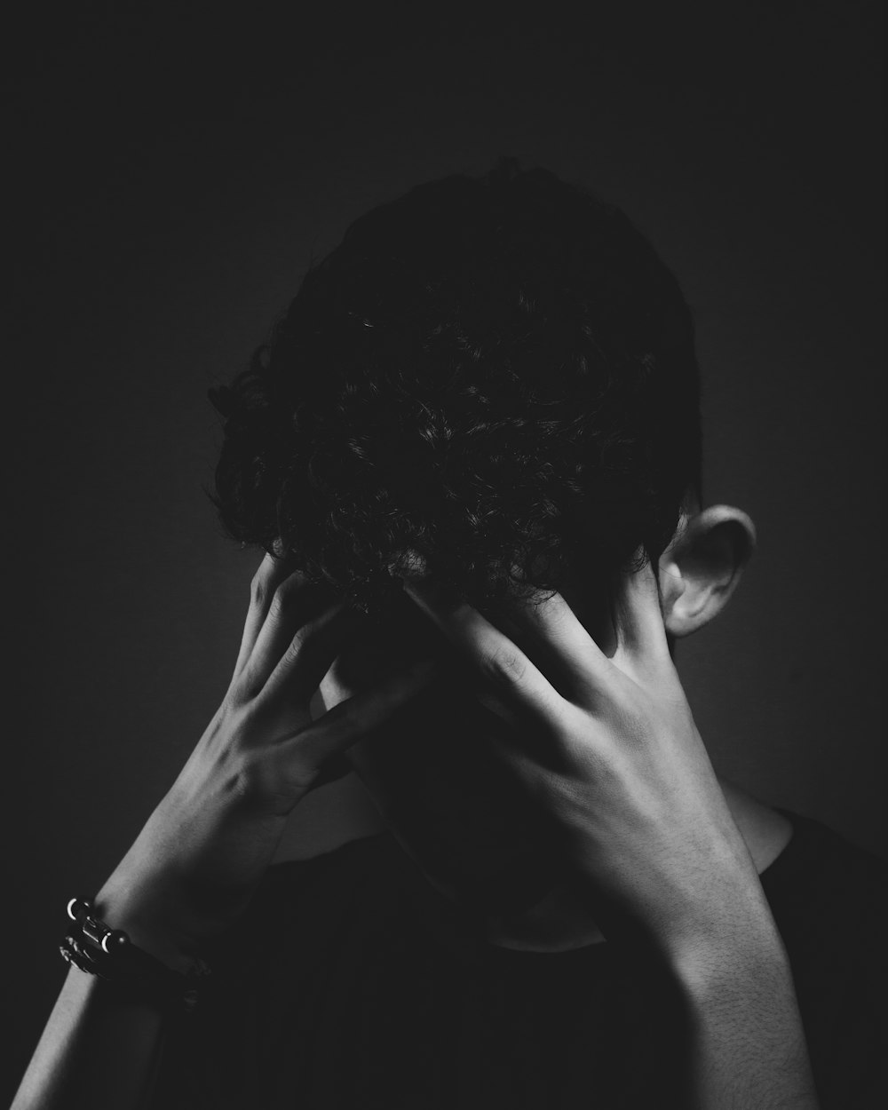 grayscale photo of man covering his face with his hand
