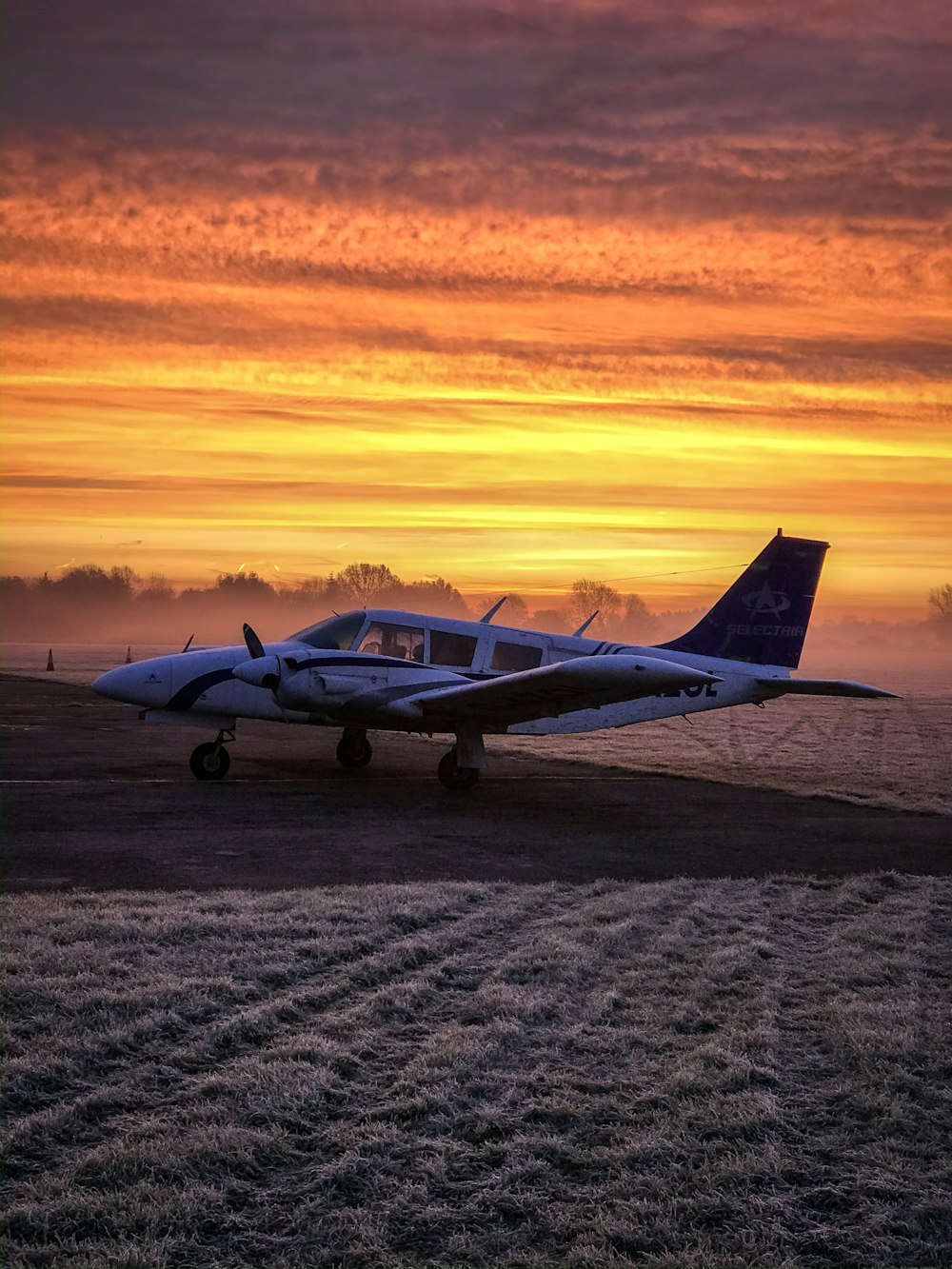 Weiß-blaues Düsenflugzeug auf braunem Sand bei Sonnenuntergang