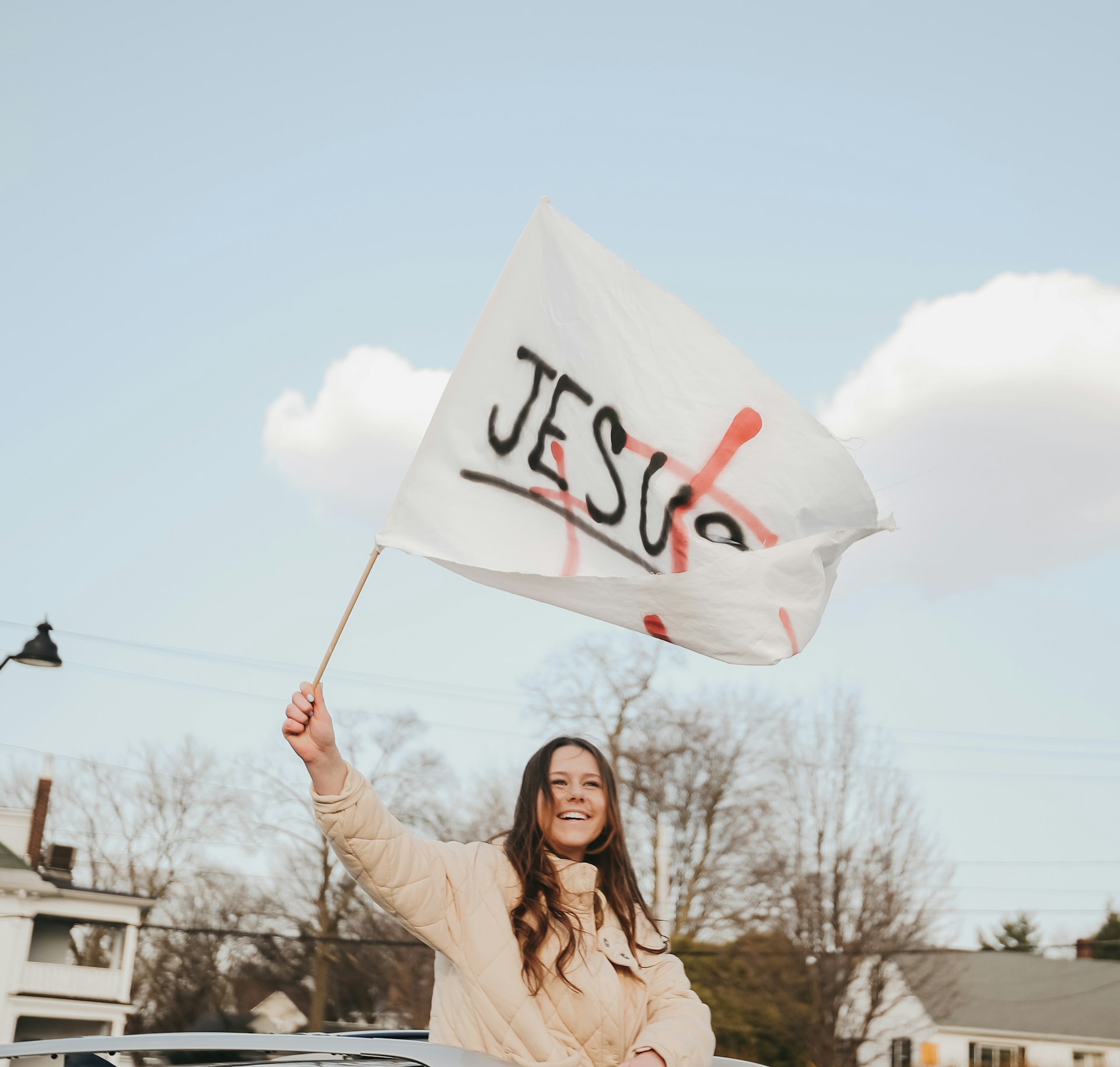 woman in beige long sleeve shirt holding white and red banner