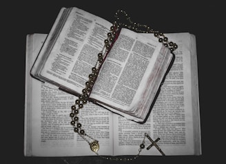 A peaceful morning scene with an open Bible and a rosary on a wooden table.
