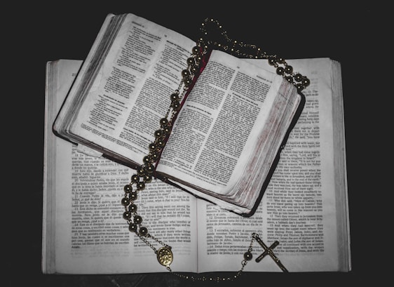 A peaceful morning scene with an open Bible and a rosary on a wooden table.