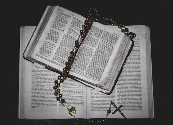 A close-up of rosary beads resting gently on a prayer book with soft sunlight.