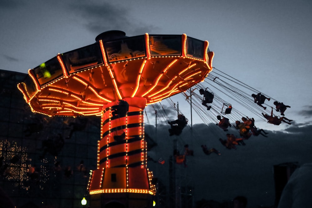 people riding on yellow and red amusement park ride during night time