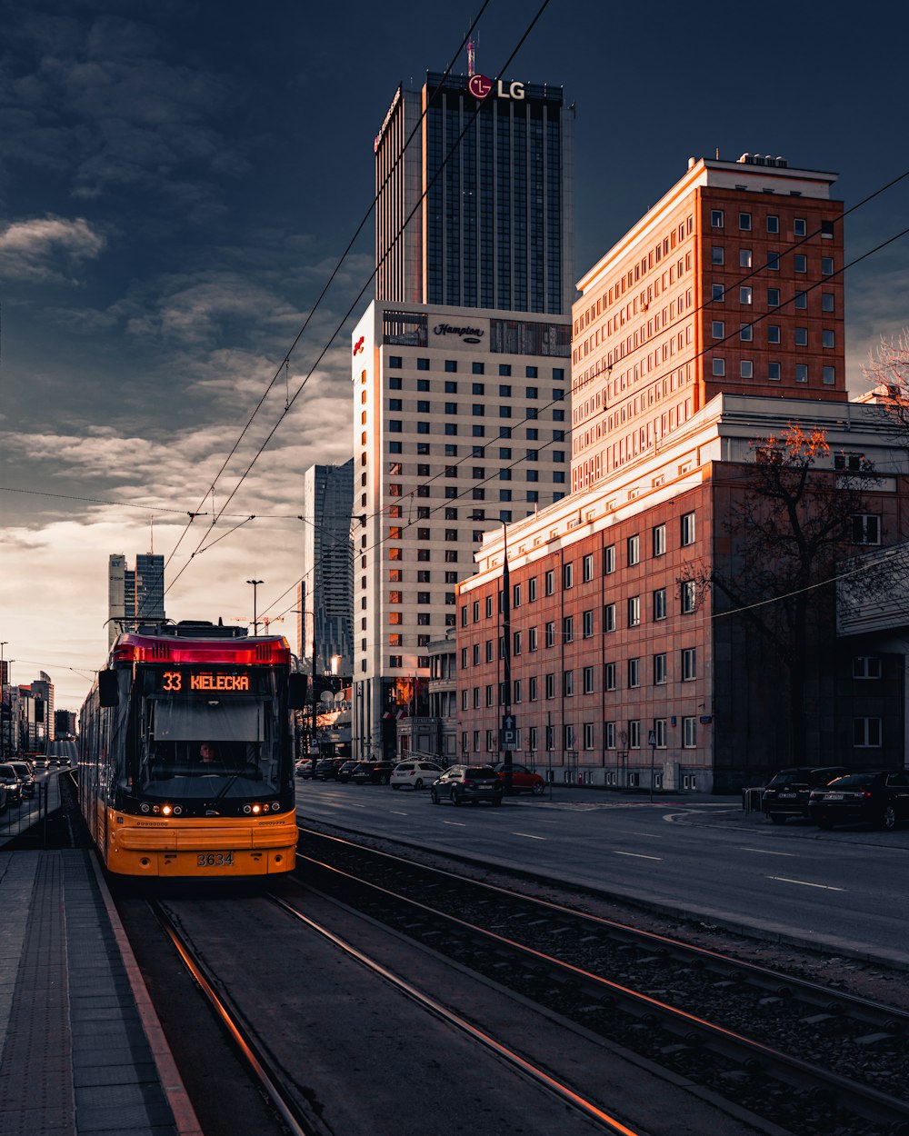 yellow and white tram on road near high rise buildings during daytime