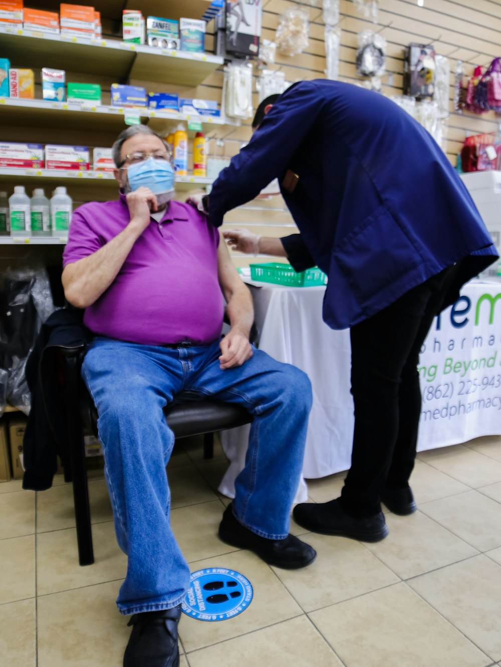 Hombre con polo morado y jeans de mezclilla azul sentado en una silla