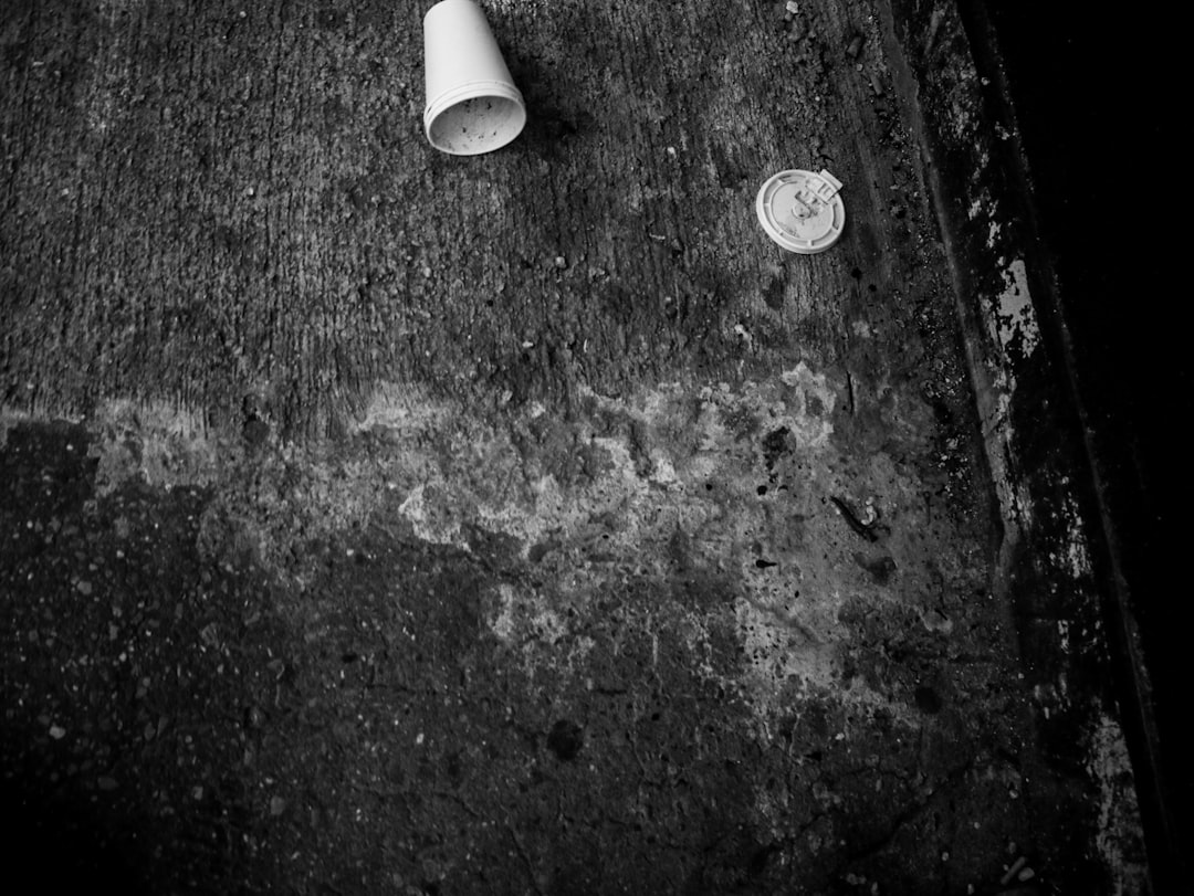 grayscale photo of round coin beside white plastic tube