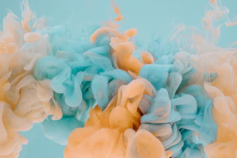 Swirling clouds of light blue and peach ink dispersing in clear water